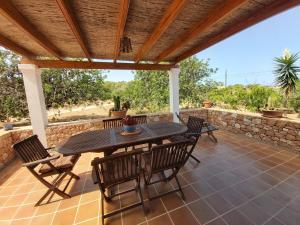 een patio met een tafel en stoelen en een stenen muur bij Casa Balbi in Sant Francesc Xavier