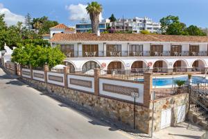 a building with a swimming pool next to a street at Apartamentos La Baranda in Torremolinos