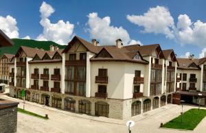 a large white building with brown roof at Happy Holidays Apartments in New Gudauri in Gudauri