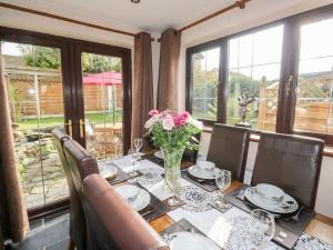 Luxurious Self Catering Holiday Cottage Cornwall في Menheniot: طاولة غرفة الطعام مع إناء من الزهور عليها