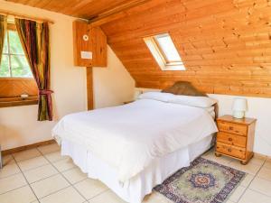 a bedroom with a white bed and a wooden ceiling at The Loft in Llangunllo