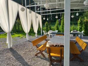 a patio with a table and chairs and white curtains at Pensiunea Aurelia in Bicaz Chei