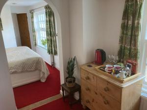 a bedroom with a bed and a dresser and a window at Bissick Old Mill Suite in Truro