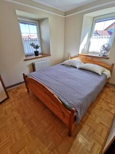 a bedroom with a wooden bed with two windows at Charming village house with patio and garden in Slovenske Konjice