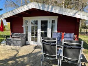 um barracão vermelho com duas cadeiras à frente em Ferienhaus am Damwildgatter em Neu Kosenow