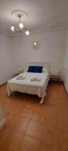 ein Schlafzimmer mit einem großen weißen Bett mit blauen Kissen in der Unterkunft Laura y Mauro in Villanueva del Fresno