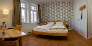 a small bedroom with a bed and a table at Hotel Alter Kreisbahnhof in Schleswig