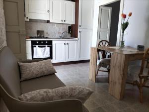 a kitchen with white cabinets and a table with a couch at Casetta Angelini in Locorotondo