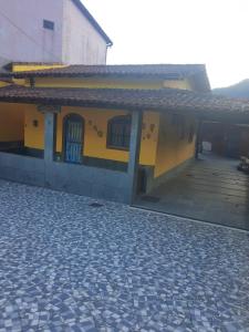 a yellow building with a porch and a patio at CASA COMPLETA-CONCEIÇÃO DE JACAREÍ -COSTA VERDE in Mangaratiba