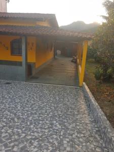 a yellow house with a walkway in front of it at CASA COMPLETA-CONCEIÇÃO DE JACAREÍ -COSTA VERDE in Mangaratiba