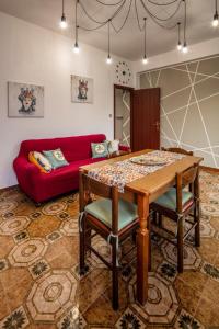 sala de estar con mesa y sofá rojo en La Valle di Hermes en Piraino