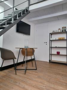 un tavolo con sedie in una camera con soppalco di All'1 di Rajno' Relaxing ApartHotel a Lecce