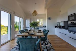 une cuisine avec une table en bois et des chaises vertes dans l'établissement O'DYSSEE Appartement vue panoramique Bassin d'Arcachon, à Pyla-sur-Mer