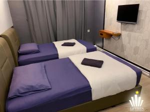 two beds in a room with purple and white at Malim Melaka Homestay in Melaka