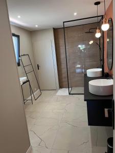 une salle de bain avec deux lavabos et une douche en verre dans l'établissement Les Camélias proche La Rochelle, à Périgny 1 autre photo