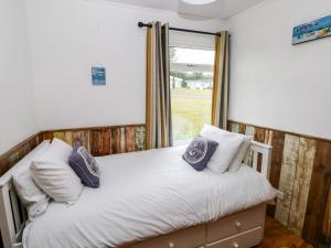 a bedroom with a bed with pillows and a window at Ty Haf in Haverfordwest
