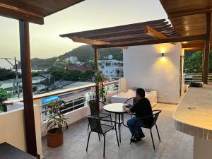 a woman sitting at a table on a balcony at Hotel Taganga Plaza Santa Marta in Taganga