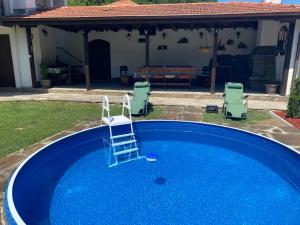 une piscine bleue avec 2 chaises longues et une maison dans l'établissement Yovkovata Kyshta, à Chiflik