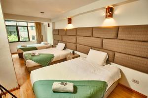 um quarto de hotel com duas camas com lençóis verdes em Inti Tampu Inn em Cusco