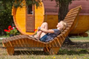 una joven sentada en una silla en un patio en Schlaffass Campingplatz Nordbrock en Hamminkeln