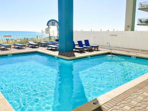 a swimming pool with lounge chairs and the ocean in the background at Grandview East 1503 in Panama City Beach