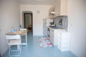 a kitchen with white cabinets and a table and chairs at ACQUAMARINA APPARTAMENT in Procida