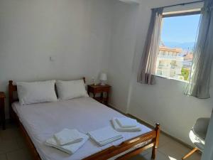 une chambre avec un lit avec des draps blancs et une fenêtre dans l'établissement Akrata v apartment, à Akrata