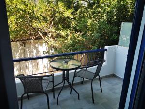 een glazen tafel en stoelen op een balkon bij Hotel Poulakis in Skala