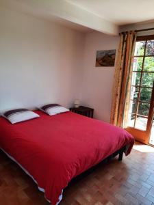 a red bed in a room with a window at Les coteaux de Planèze, maison et jardin dans le Lot! Chambres chez l'habitant! in Belmont-Bretenoux