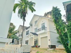頭頓的住宿－Vung Tau Beach Villa- Back Beach Villa- 4 Bedrooms Villa，前面有棕榈树的白色房子