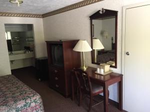 a hotel room with a desk and a bed and a mirror at Deerfield Inn in Somerville