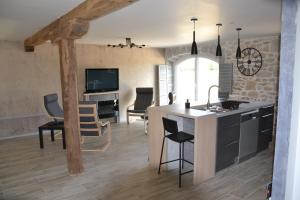 een keuken en een woonkamer met een tafel en stoelen bij Gite Entre Causse et Vallon, tout confort pour 4 personnes dans grange rénovée au coeur de l'Aveyron in Salles-la-Source