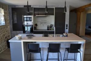 a kitchen with a large island with bar stools at Gite Entre Causse et Vallon, tout confort pour 4 personnes dans grange rénovée au coeur de l'Aveyron in Salles-la-Source +10 photos