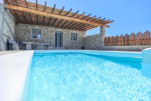 una piscina con una villa en el fondo en The George Villas Mykonos with Private Pool & Town Proximity, en Mykonos ciudad