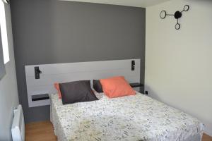 een slaapkamer met een bed met oranje kussens erop bij Gite Entre Causse et Vallon, tout confort pour 4 personnes dans grange rénovée au coeur de l'Aveyron in Salles-la-Source