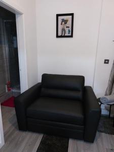 un sofá de cuero negro sentado en una sala de estar en Limpenny Garden Flat, en Nottingham