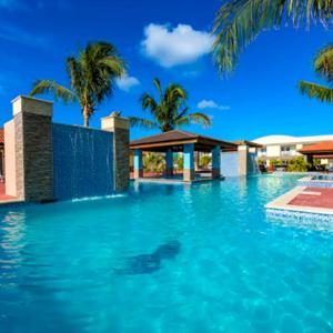 a swimming pool with blue water and palm trees at Family Apartment with Pool in Aruba in Palm-Eagle Beach