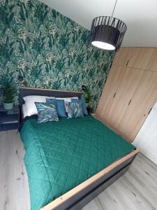 a bed with a green comforter in a room at Apartament Bernata-Śródka in Poznań