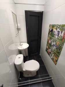 a bathroom with a white toilet and a sink at Cucú Ardilla Vivienda Campestre en Pance in Cali