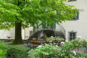 a building with stairs and a tree and flowers at Hotel Palazzo Salis in Soglio