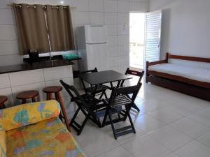 a kitchen with a table and chairs and a bed at Apartamentos Margarida in Ubatuba