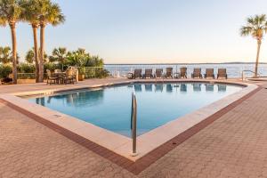 a swimming pool with chairs and the ocean in the background at East Pass 308 in Destin