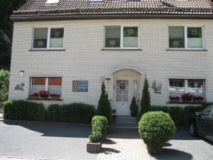 Ferienwohnung Am Berg في Wieda: منزل من الطوب الأبيض مع باب أبيض ونوافذ