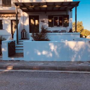 une maison blanche avec une clôture devant elle dans l'établissement Cozy flat with garden, à Tinos