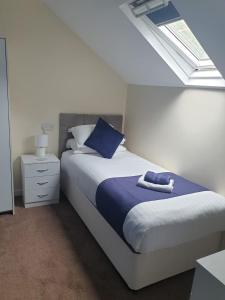 a bedroom with a bed with a blue pillow and a window at Leamington House in Barmouth