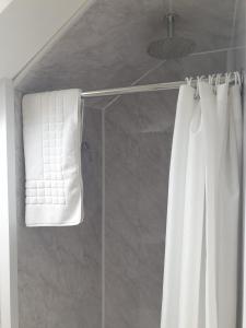 a shower with a white shower curtain and a towel at Leamington House in Barmouth