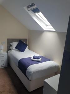 a bedroom with a bed with blue pillows and a window at Leamington House in Barmouth