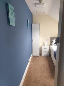 a bedroom with a mirror and a bed with blue walls at Leamington House in Barmouth