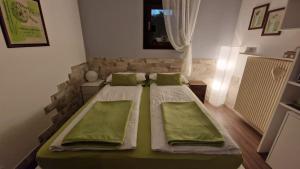 マドンナ・ディ・カンピリオにあるTanazenのベッドルーム1室(緑の枕が付いたベッド2台付)