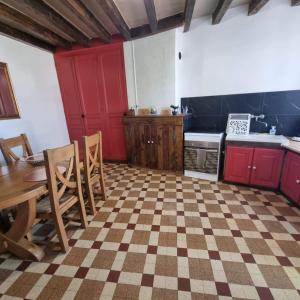 une cuisine avec des placards rouges, une table et des chaises dans l'établissement A la 4L, à Noyers-sur-Cher